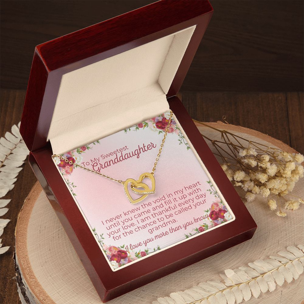 interlocking hearts necklace for granddaughter from grandma, grandpa or grandparents. it comes with a heartfelt message that reads, "I never knewe the void in my heart until you came and fill it up with your lvoe. I am thankful every day for the chance to be called your grandma" It is in a mahogany style box with led lights